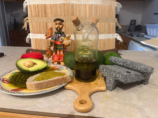 Artisanal avocado oil from Guatemala with fresh bread, avocado, and traditional stone grinder.